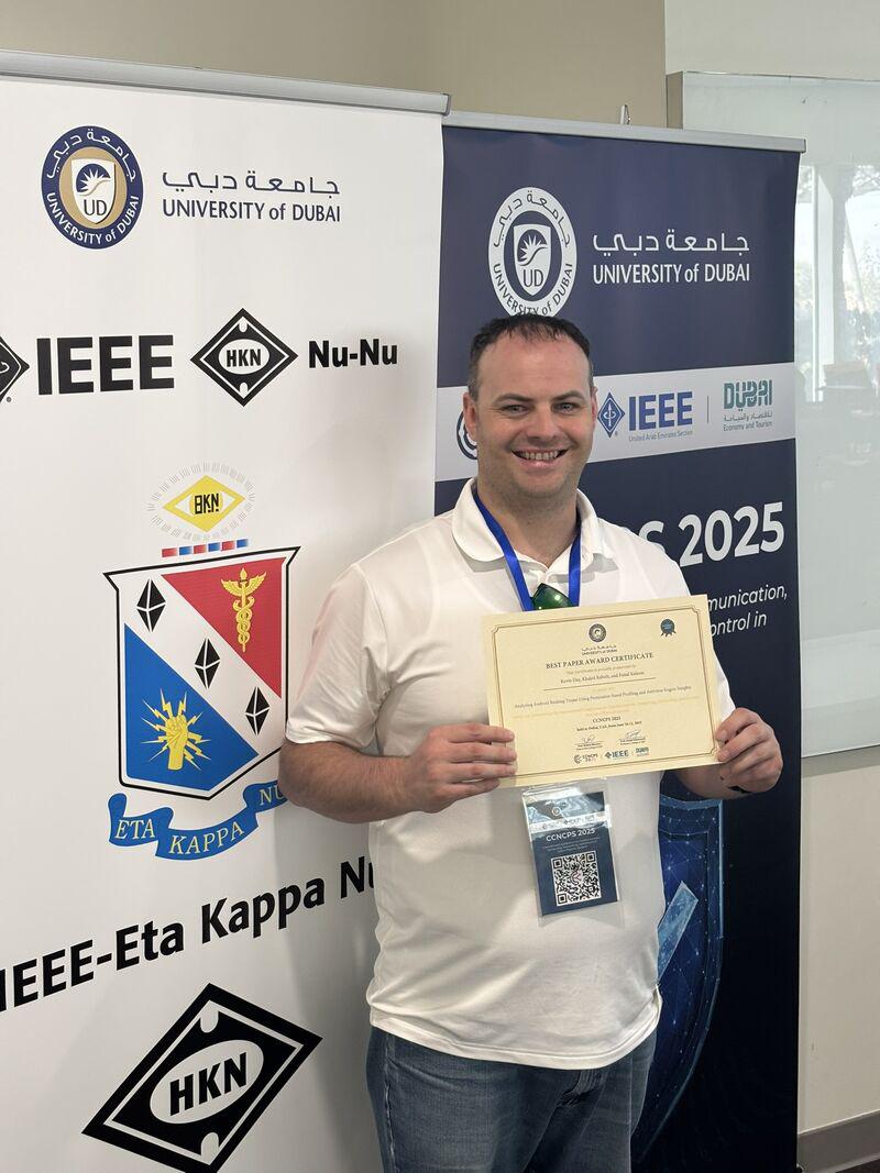Metro State graduate Kevin Day poses with his Best Paper Award at the IEEE International Conference on Cyber-Physical and Networked Control Systems (CCNCPS 2025), held in Dubai, UAE