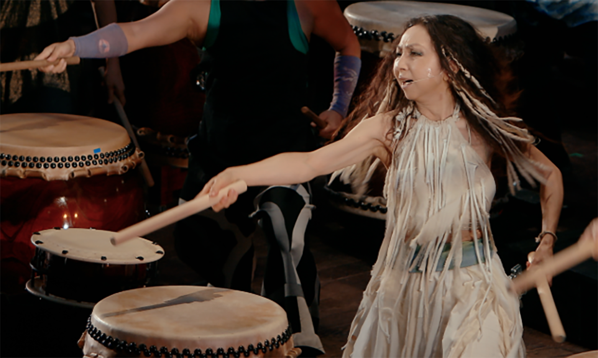 a woman leads a drum group