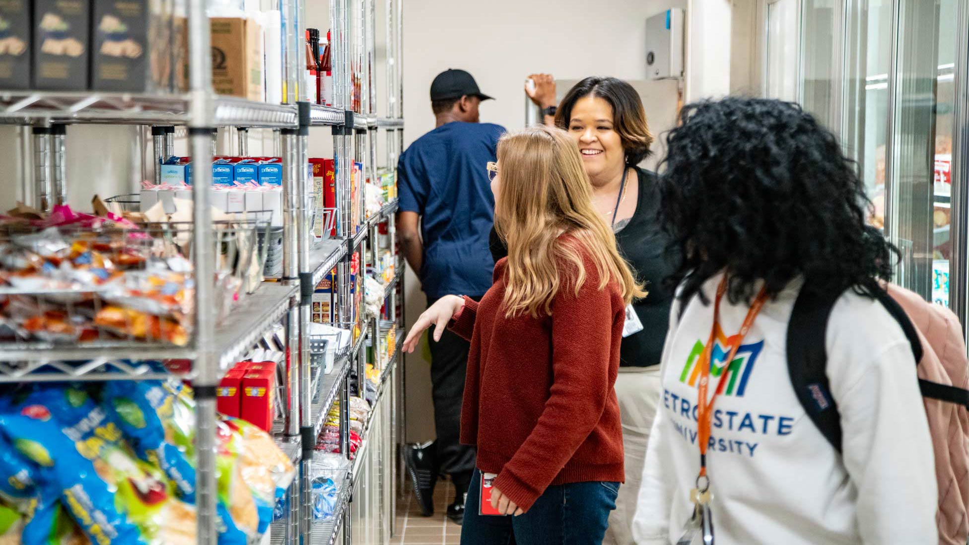 Image shows four students walking through Metro State's food for thought pantry to collect items.