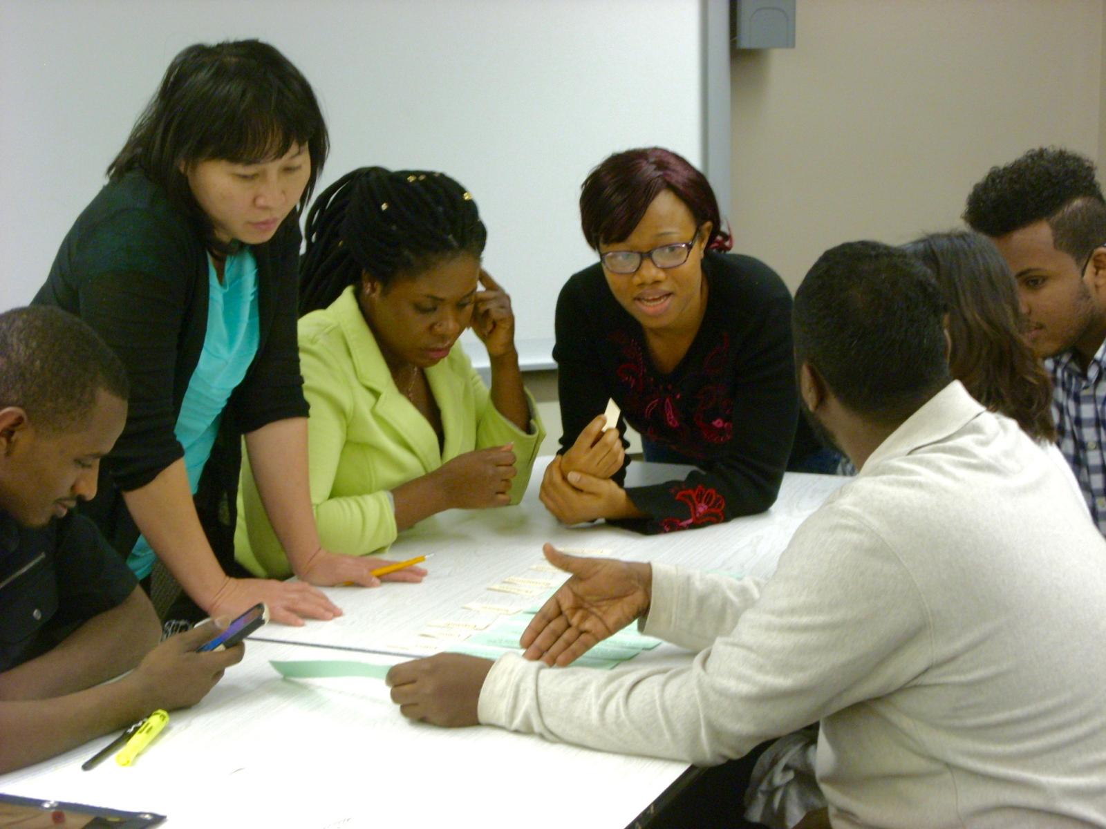 seven young people talking while sitting around a table