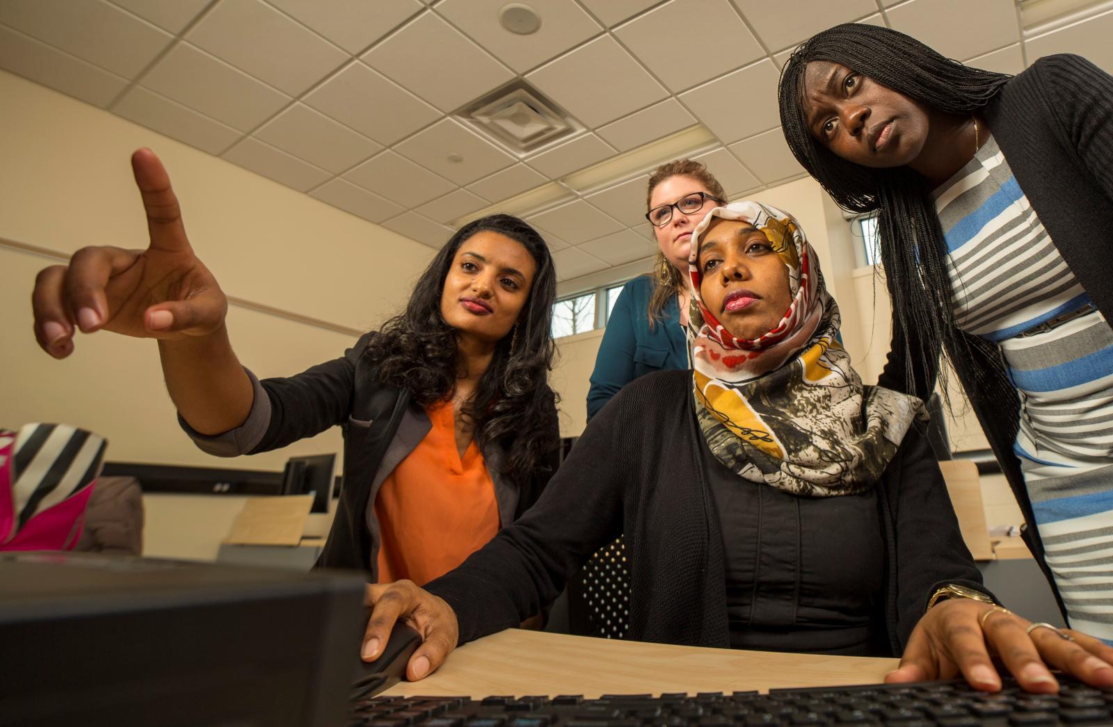 Professor pointing and three female students looking