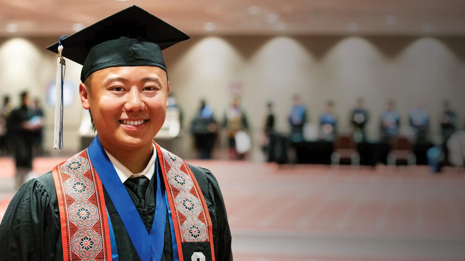 A student in cap and gown smiling 