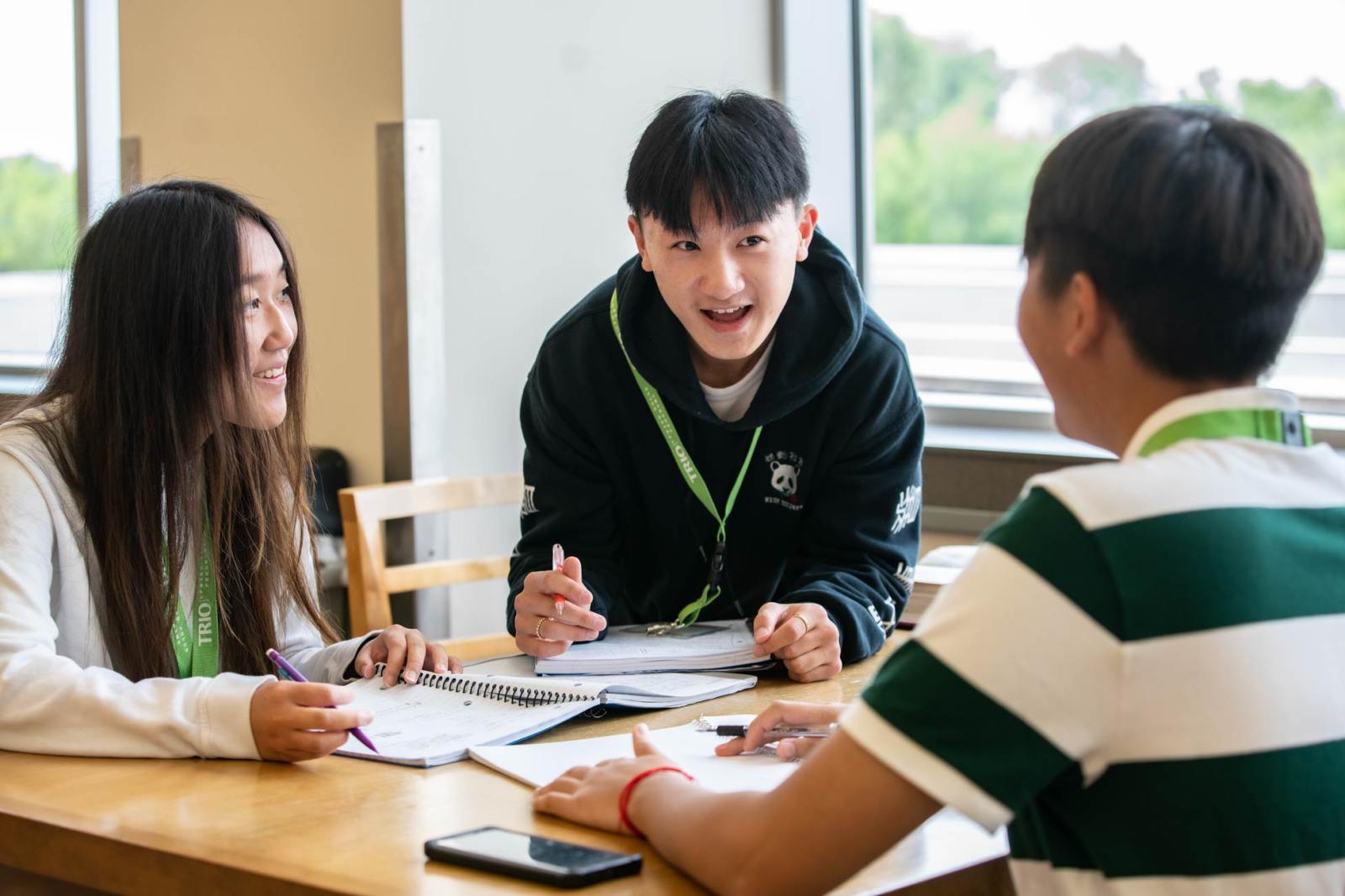 Three students talking together at a table