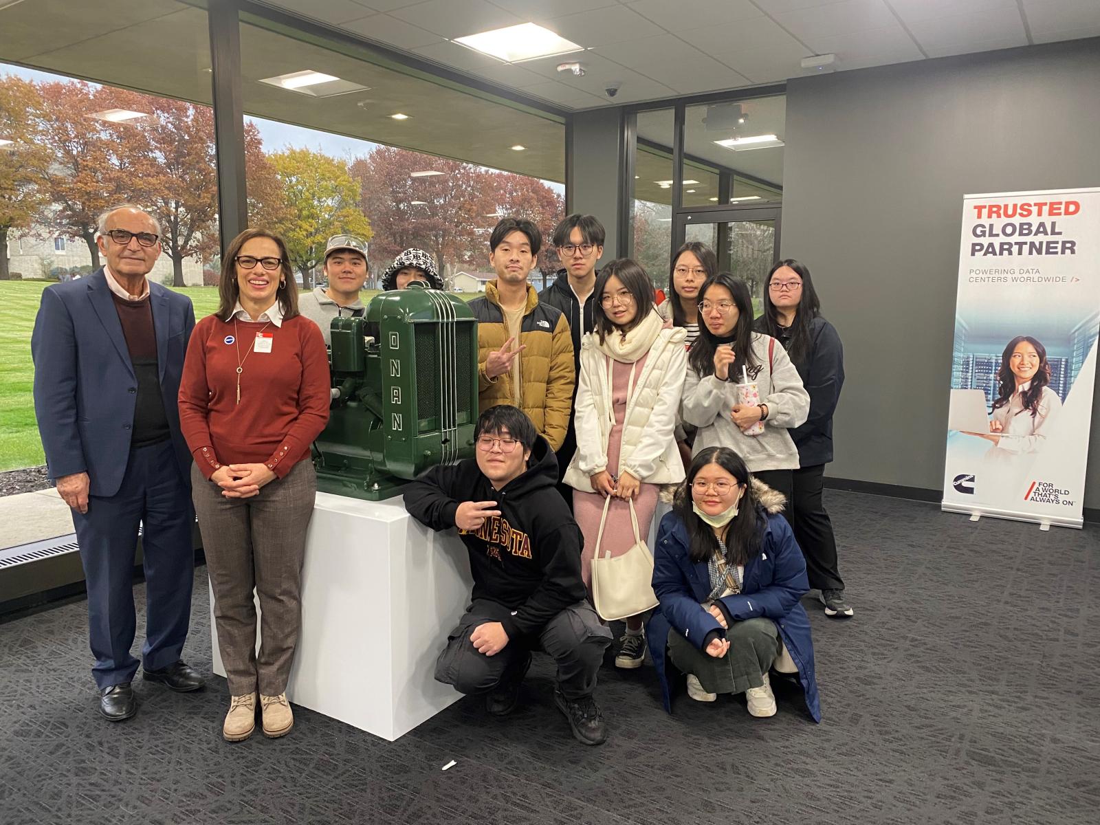 A group of people pose for a picture with a piece of equipment. 