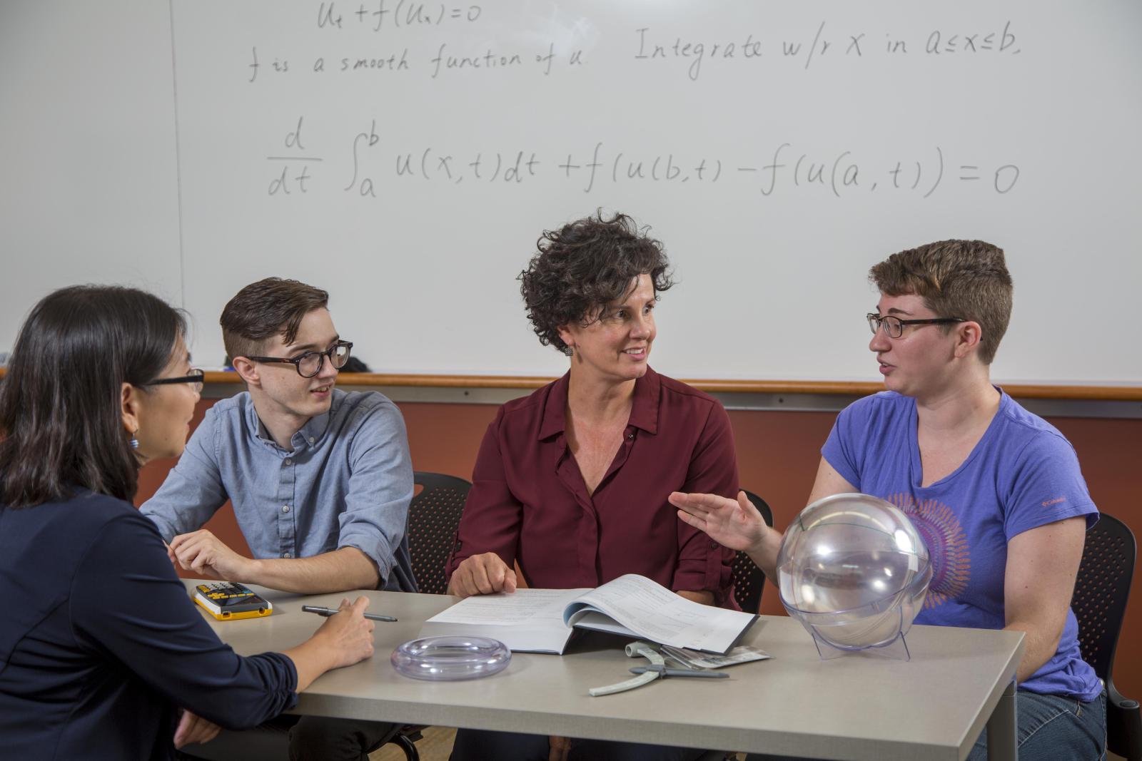 Students and a professor discuss around a table