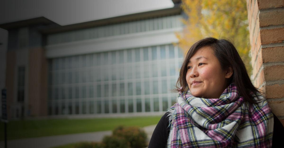 A woman in a plaid scarf standing outside in front of New Main