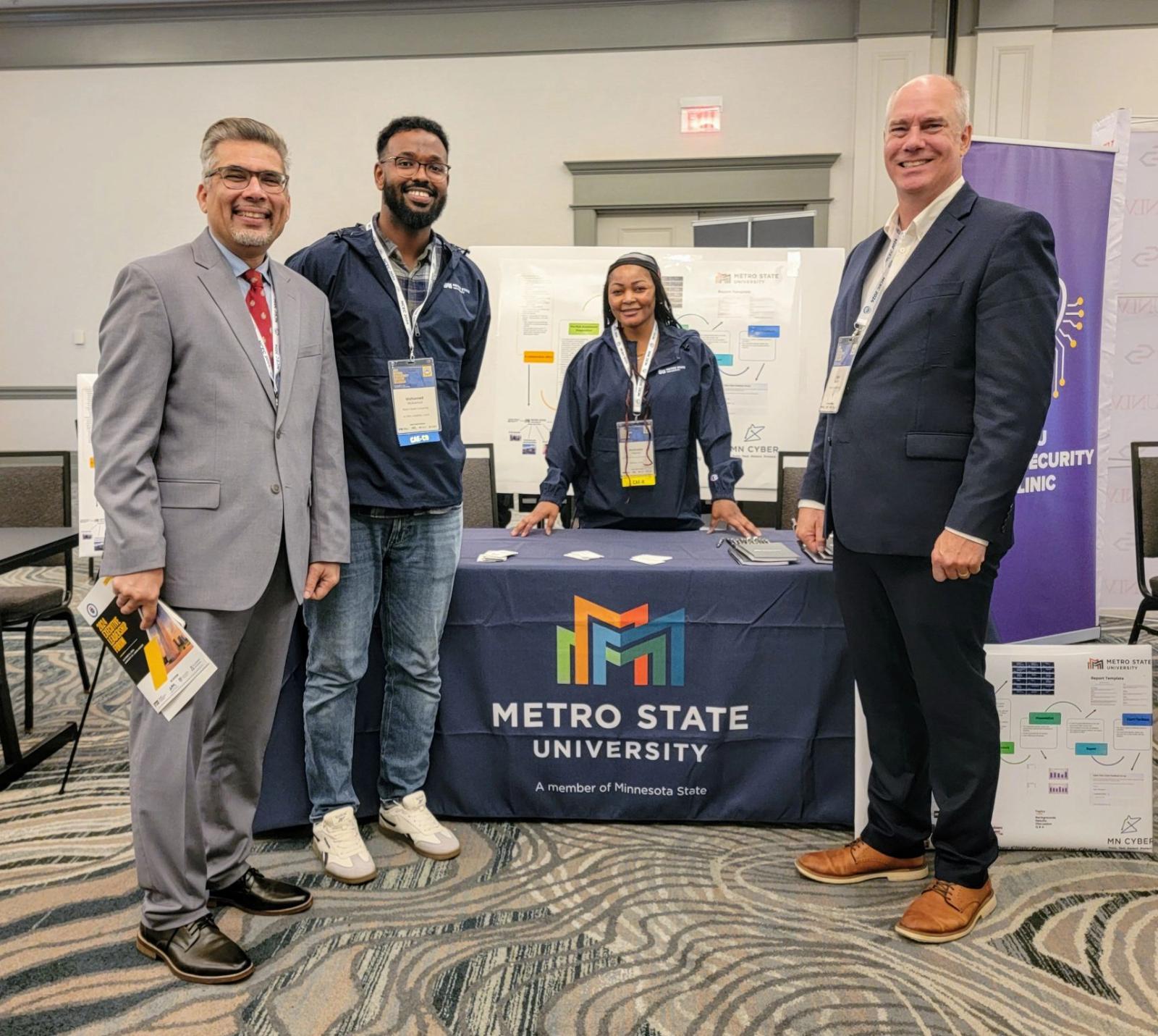 People pose near the Metro State University booth at the CAE in Cybersecurity Colloquium